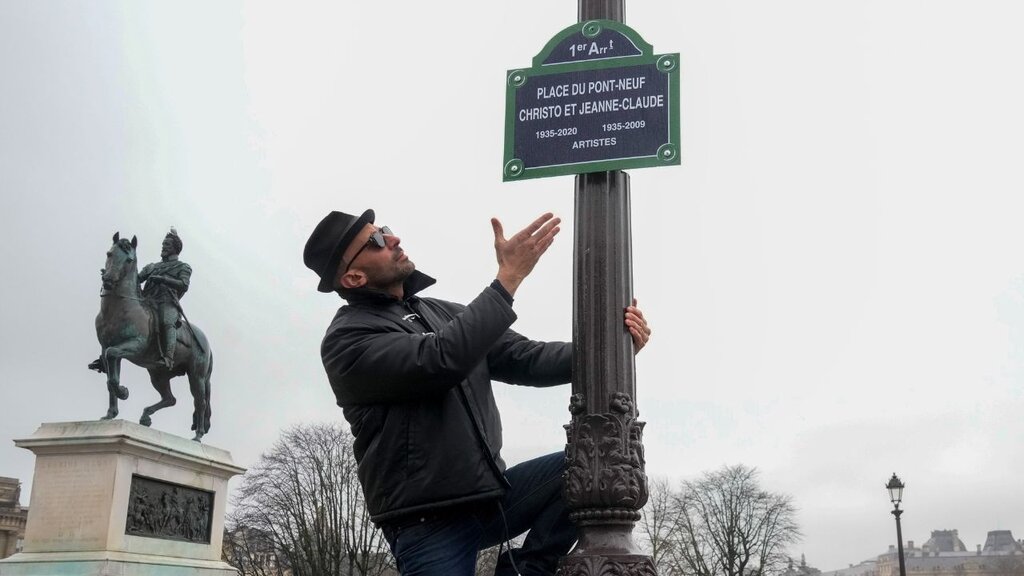 Der französische Künstler JR zeigt das Schild des Platzes „Pont Neuf – Christo et Jeanne-Claude“ in Paris.